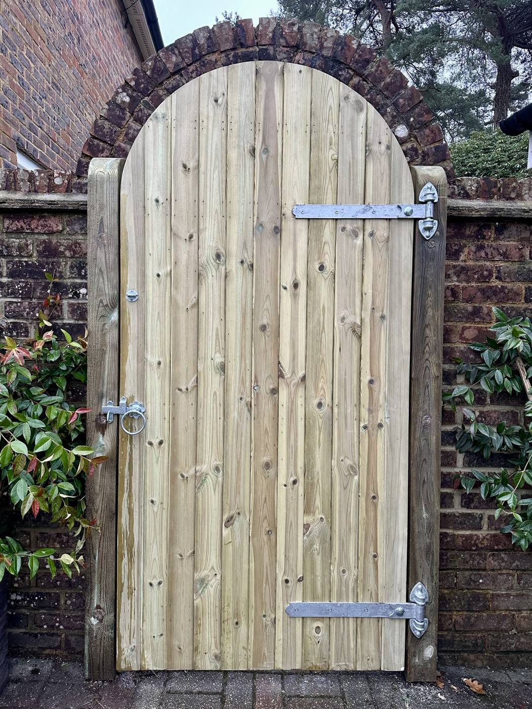 Arched timber garden gate in a brick wall