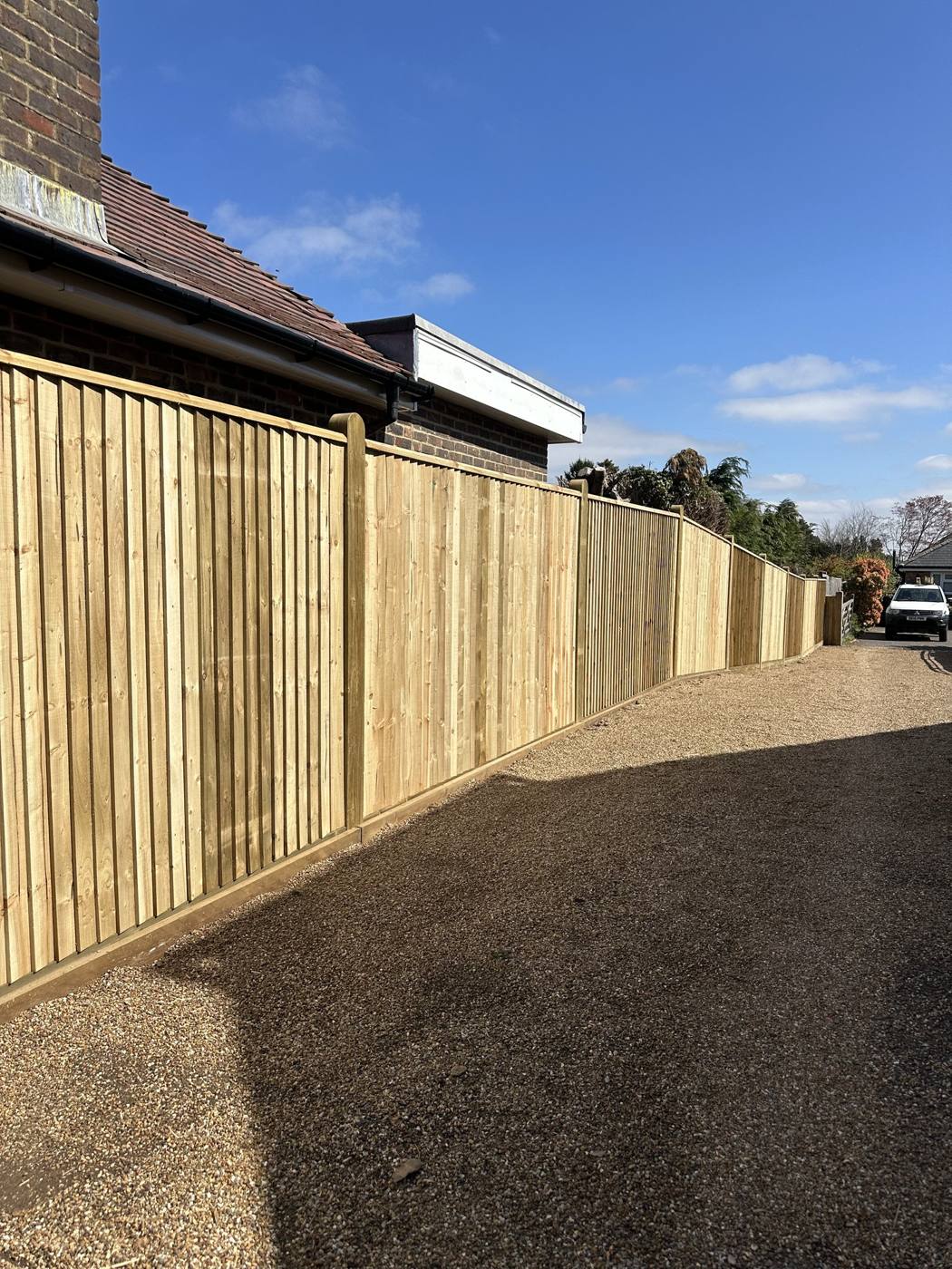 Close board fence along a gravel drive